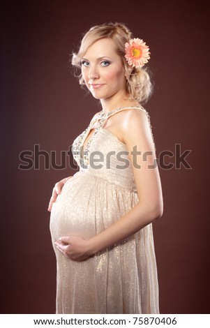 Studio portrait of a glamorous blonde pregnant woman in a beautiful evening gown