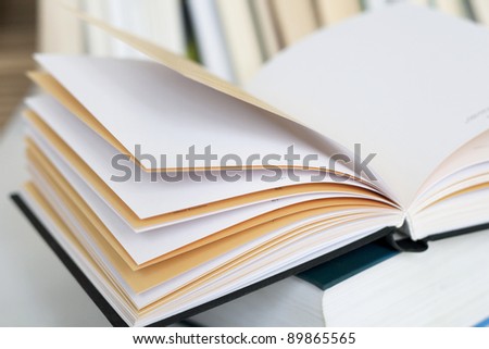 Opened book with empty pages on other book in books background