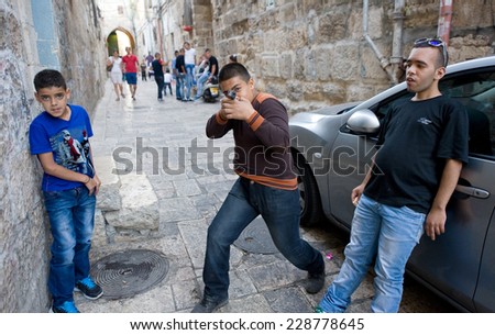 ISRAEL, JERUSALEM - OCTOBER 06, 2014: Three young muslim teenagers are playing \'war games\' on the streets in the muslim quarter in the old city of Jerusalem