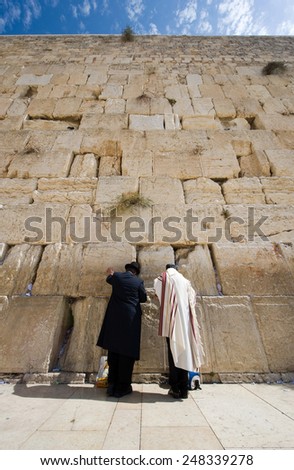 Two jewish men are praying in front of the western wall in the old city of Jerusalem