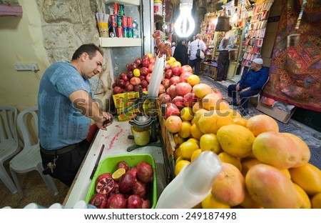 JERUSALEM, ISRAEL - OCTOBER 07, 2014: A man is making juice from a pomegranate in one of the small streets in the old city of Jerusalem
