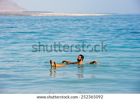 DEAD SEA; ISRAEL - 16 OCTOBER, 2014: A man floating in the salty water of the dead sea in Israel