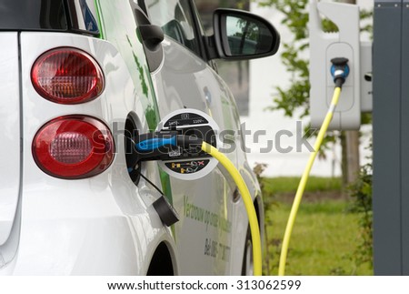 ENSCHEDE, THE NETHERLANDS - JUNE 02, 2015: An electric car is parked at a parking spot and is being recharged at a power station.