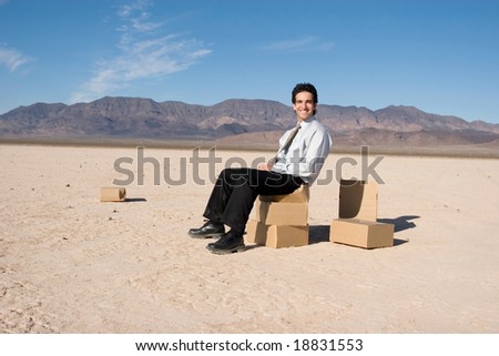 Businessman sitting on boxes in the desert