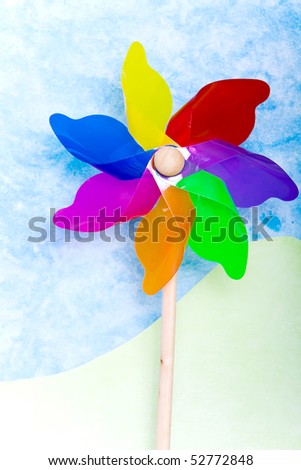 Colorful windmill toy on conceptional handmade from paper green hills and blue sky