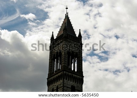 bell tower stands tall and solid against a cloud filled sky