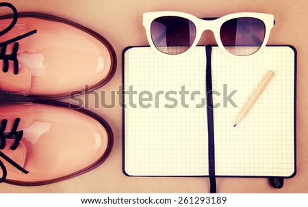 Shiny beige shoes on low heels, white sunglasses, wooden pencil and small black paper notebook. Vintage style edition.