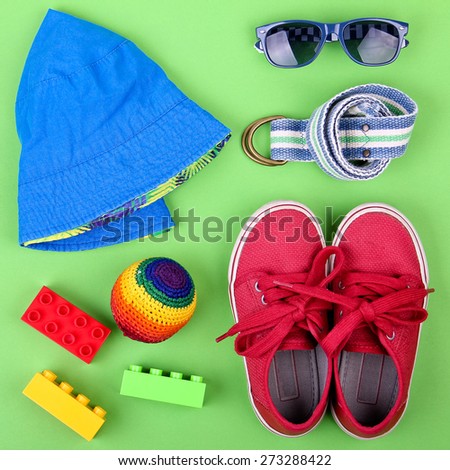 Kid's street outfit and some toys on green background. Overhead view.