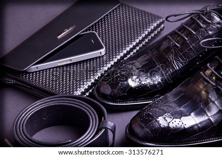 Stylish men\'s shoes, purse, cellphone and black belt on gray background. Crocodile leather.