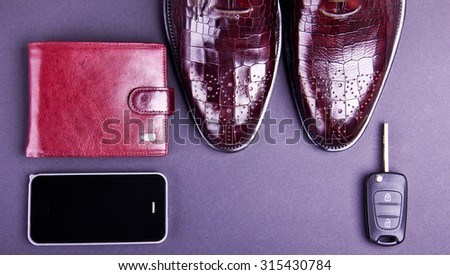 Stylish men\'s shoes, cellphone, car key and wallet on gray background. Crocodile leather. Place for text.