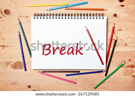 writing pad on wood table with colored pencil - break