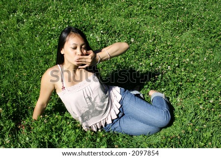 Asian young woman with long black hair sitting on grass is kissing