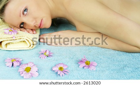 a fresh and beautiful blond woman laying on a towel with flowers