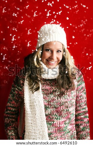 winter portrait of a beautiful young woman with a cap and a scarf and flying snow