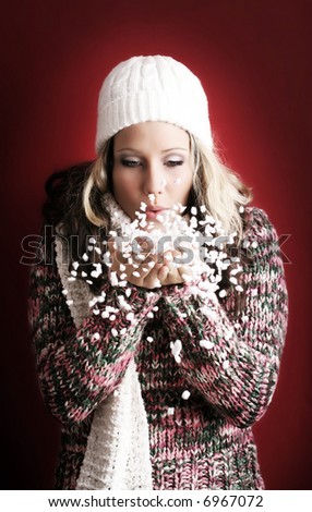 winter portrait of a beautiful young woman with a cap and a scarf and flying snow