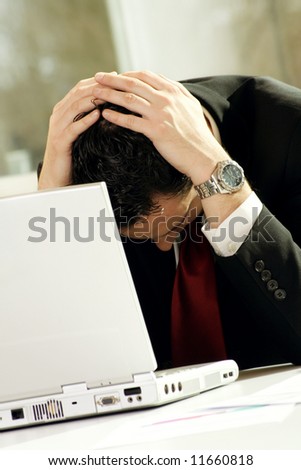 a successful business man is frustrated on a table with a laptop