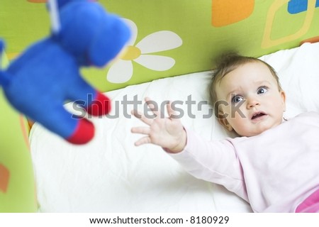 Baby in a crib - reaching for a toy