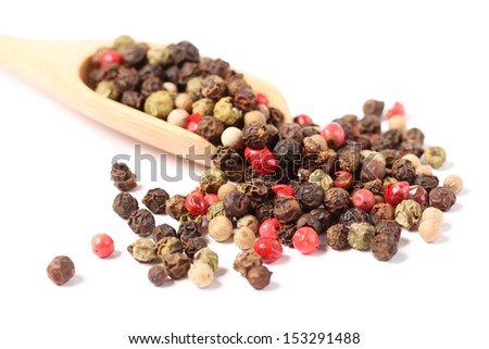 Mixed red, white and black pepper corn seed spilled out of the bamboo spoon