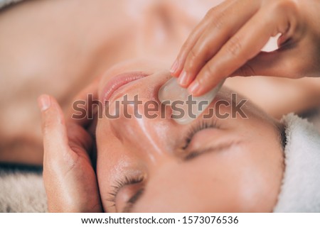 Guasha face massage with jade stone. Close-up of a young woman’s face Foto stock © 