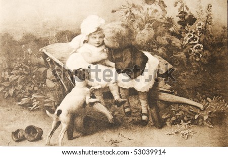 GERMANY - CIRCA 1902: Vintage postcard made of a photograph of two small children and a dog.  Elder boy kissing his sister. circa 1902