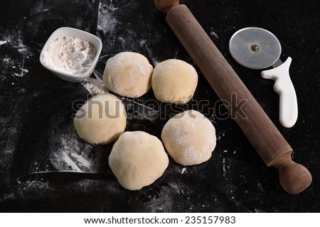 Small balls of fresh pizza dough on wooden board.