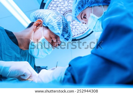 two veterinarian surgeons in operating room take with blue filter