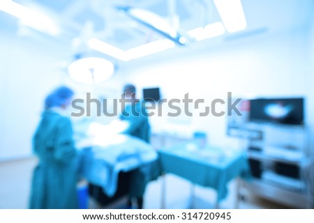 Blur of two veterinarian surgeons in operating room take with art lighting and blue filter