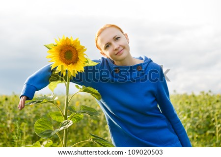 Young red woman hugs sunflower in the field