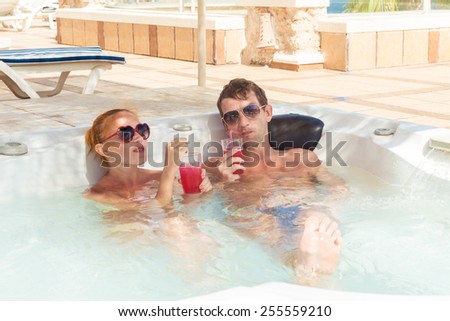 Smiling loving couple relaxing together on a jacuzzi pool at tourist resort