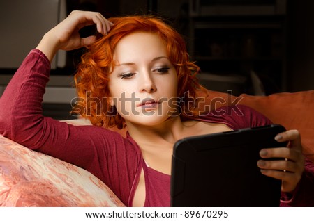 Woman relaxing with her ebook reader or tablet computer at home
