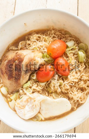 Instant noodle\
Grilled Chicken\
boiled egg\
onion\
Pork soup\
In a white cup\
Placed on the wooden floor