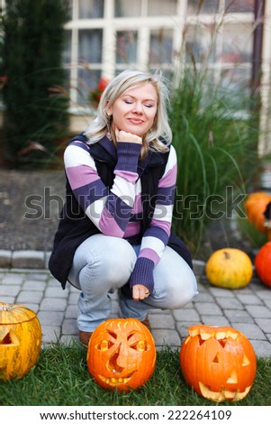 Woman squat at halloween pumpkins, outdoor portrait