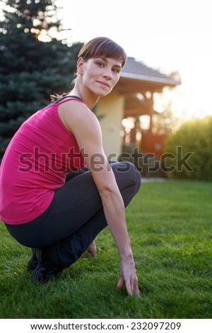 Young woman squat in sportswear during sunset, outdoor portrait