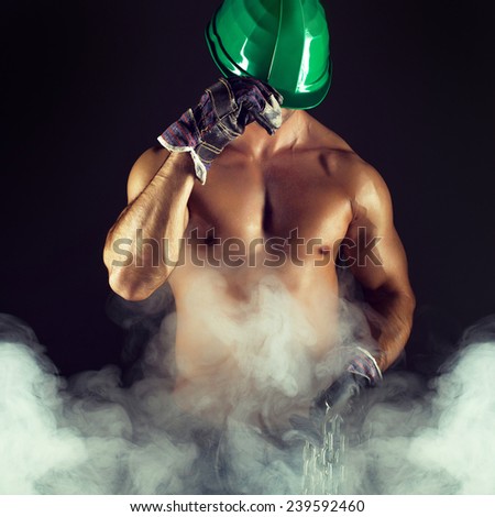 Sexy macho worker in helmet, gloves and fog