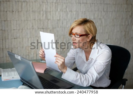 Blonde businesswoman in glasses reading letter, bad news