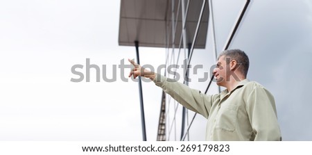 Young businessman pointing to sky at business center