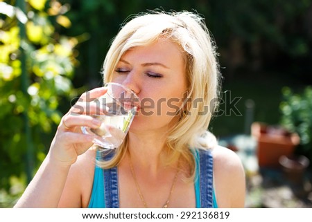 Blonde woman drinking water on hot summer day, outdoor portrait