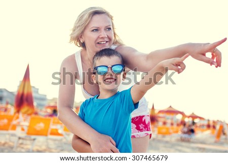 Mother with son showing away on beach, retro style
