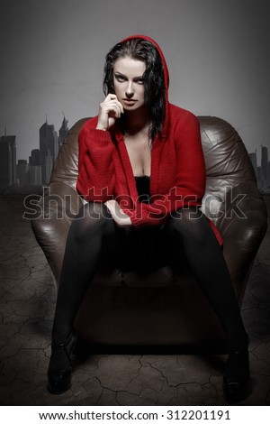 Sexy woman in desert sitting on sofa, utopia, global warming