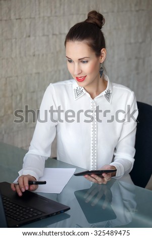 Modern businesswoman typing on laptop, red lips, in office