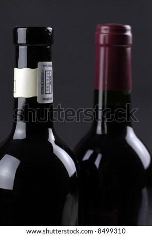 low-key image of two dark wine bottles against dark ground