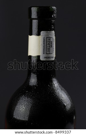 low-key image of dark wine bottle covered with condensation, against dark ground; background easily extendable to increase copy space