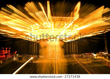zoom exposure of brightly-lit chair-o-plane fairground ride; prominent, exciting light-trails