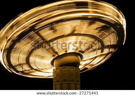 detail of brightly-lit chair-o-plane fairground ride; light trails