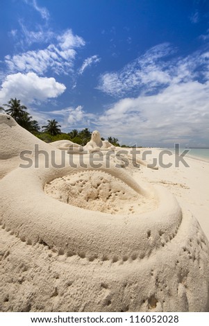 Greek God Neptun built of sand rests at the beach andi looks to the sea