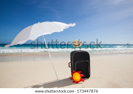 black trolley, straw sun hat and yellow frisbee under a white sunshade at a beautiful beach with a turquoise sea and a blue sky, Seychelles, Africa
