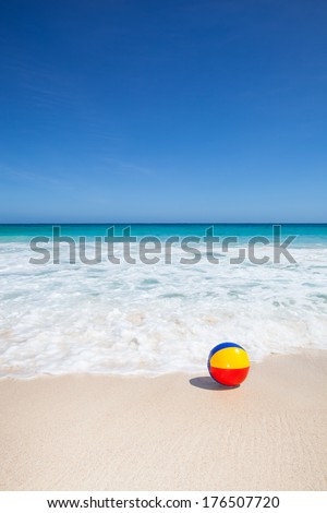 travel background with a colorful water ball at the beach and a turquoise sea and a blue sky in the background