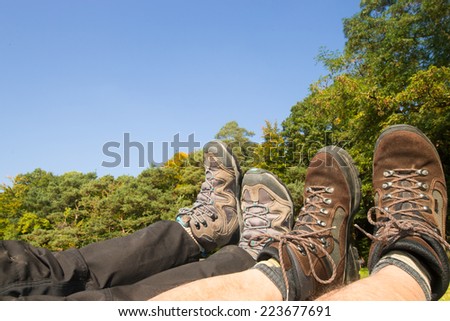 resting legs with two pairs of brown and grey hiking boots after rambling in the forest