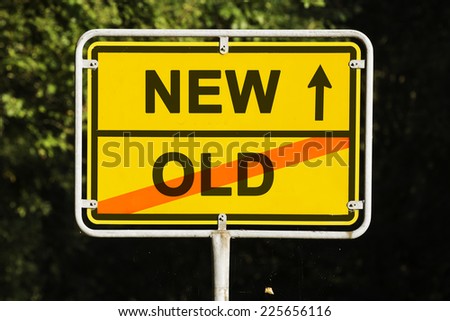 Blue sky behind a yellow city limit or place name sign informing with an arrow that you are on the way to NEW and leaving OLD