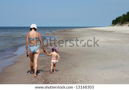 Mother and child walking in the empty beach on hot summer day